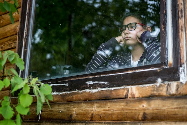 Portrait of the boy looking through the window