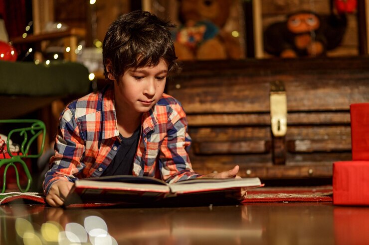 फोटो portrait of boy lying on the floor and reading a book in room with christmas decor
