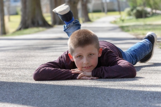 Photo portrait of boy lying on road