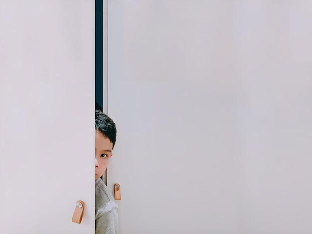 Photo portrait of boy peeking through door