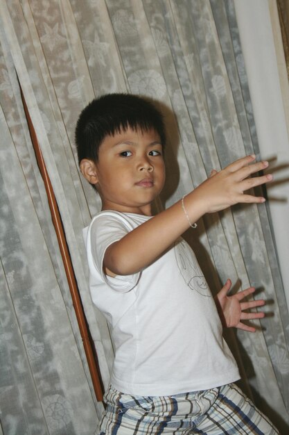 Photo portrait of boy posing against curtain at home