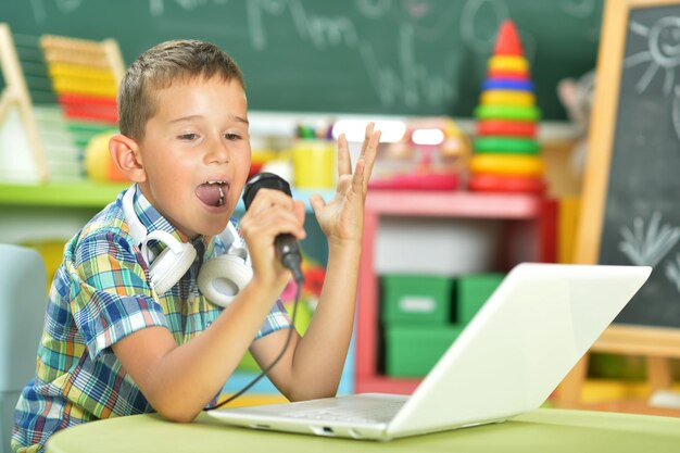 Portrait of boy singing karaoke with microphone and laptop