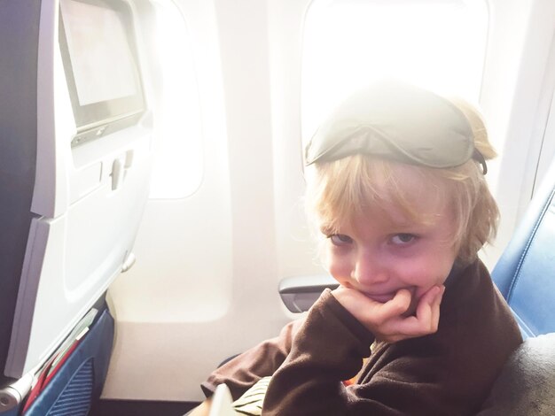 Photo portrait of boy sitting in airplane on sunny day