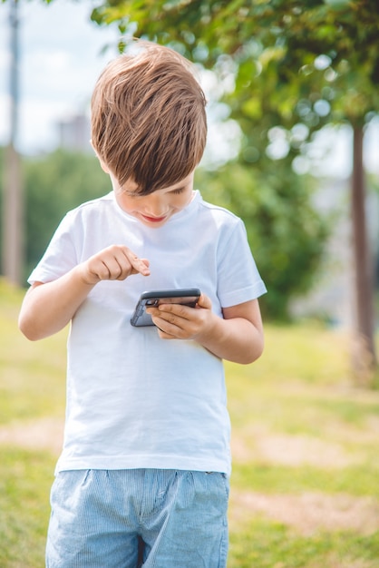 portrait boy sitting on the grass with phone