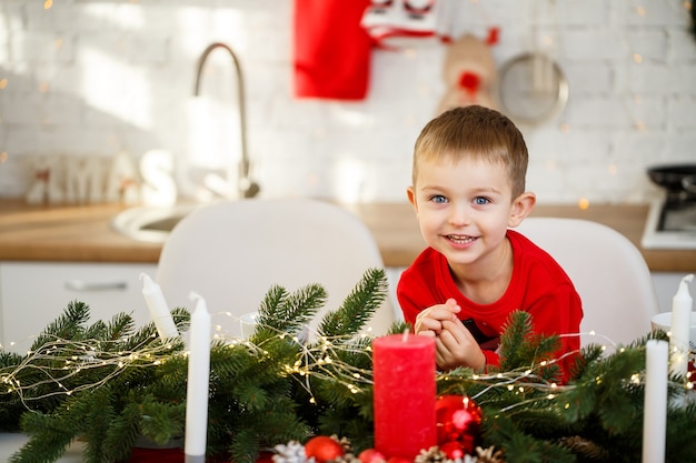 新年に飾られたクリスマステーブルのキッチンに座っている男の子の肖像画。キッチンのクリスマスの装飾