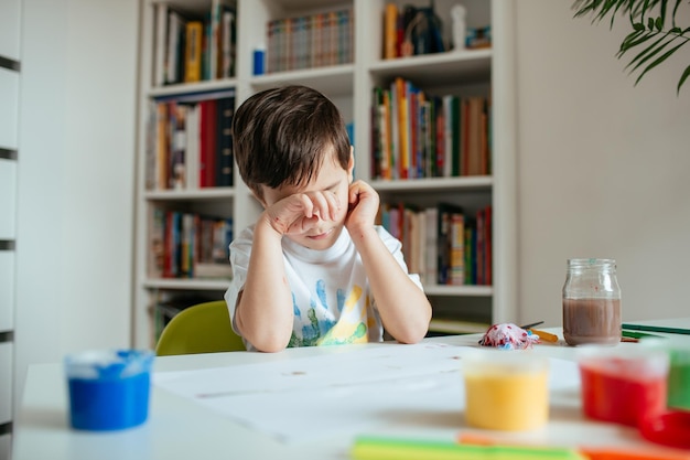 Portrait of boy sitting on table at home