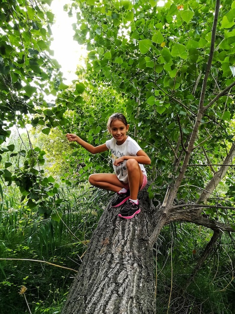 Photo portrait of boy sitting on tree trunk