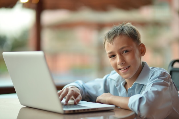 Portrait of a boy sitting with laptop in hotel