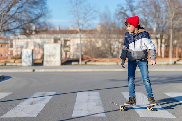 Portrait of boy skateboarding on road against trees