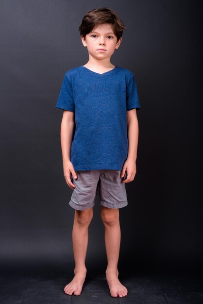 Photo portrait of boy standing against black background