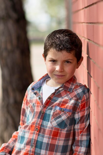 Photo portrait of boy standing by brick wall