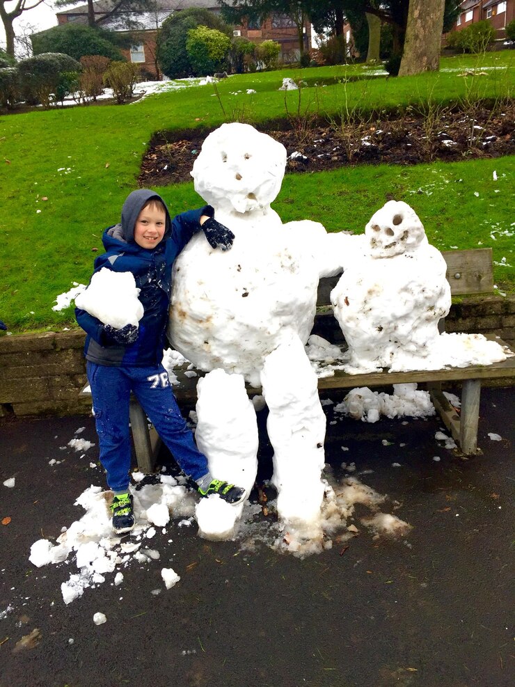 Photo portrait of boy standing by snowman at park
