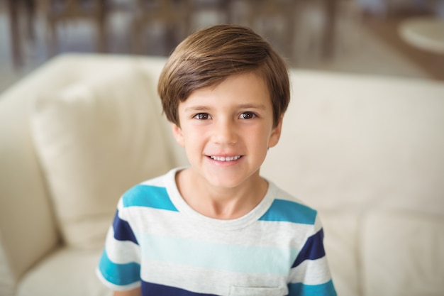 Portrait of boy standing near sofa in living room