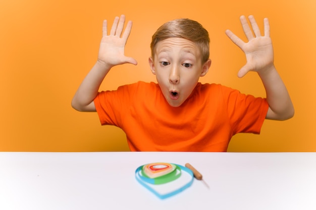 Portrait of boy on table against orange background