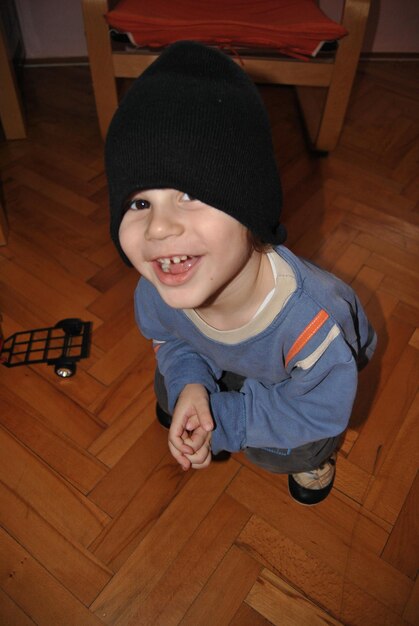 Portrait of boy wearing knit hat while crouching on hardwood floor