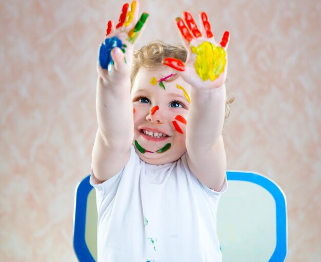 Photo portrait of boy wearing multi colored umbrella against wall