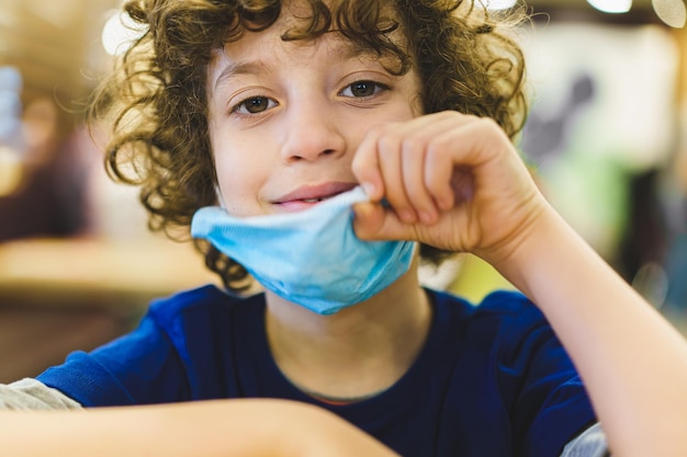 Portrait of a boy wearing a protective mask to reduce the spreding of covid19 sitting outdoors