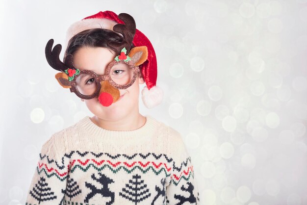 Photo portrait of boy wearing santa hat while standing against white background