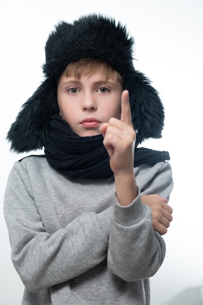 Portrait of a boy on a white background in a hat with ears and a scarf