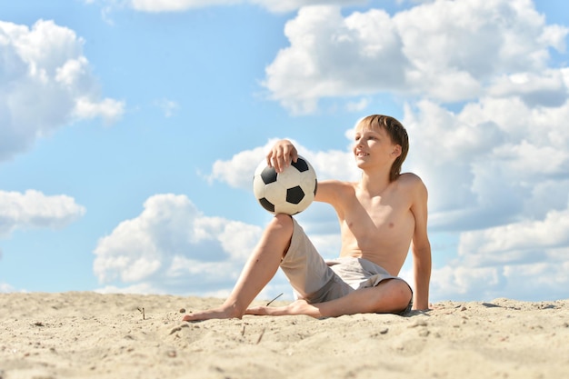 Portrait of boy with ball on beach in summer day