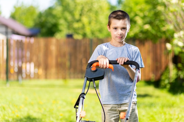 Portrait a boy  with an electric lawn mower mowing the lawn.Beauty boy  pruning 