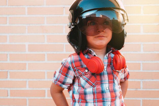 Photo portrait of boy with russian pilots helmet on brick wall