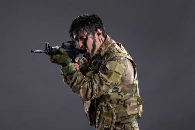 Portrait of brave soldier in camouflage during operation on dark wall