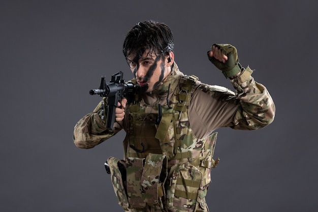 Portrait of brave soldier in camouflage with machine gun on dark wall