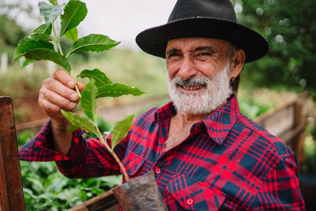 Portrait of Brazilian farmer man in the casual shirt in the farm analyzing coffee seedlings