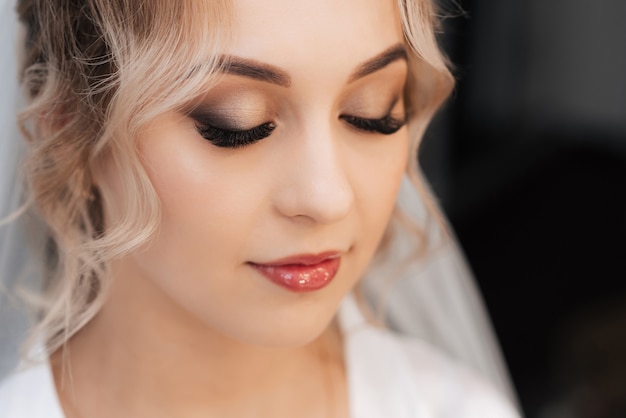 Photo portrait of a bride in a beauty salon, beautiful blonde with hair and makeup in a veil.