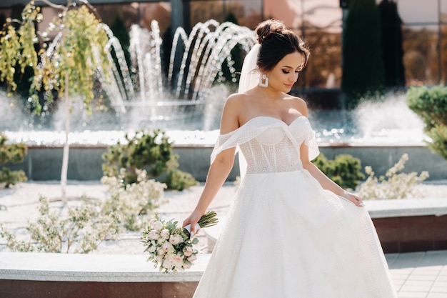 Portrait of the bride in the city near the fountain.A stunning young bride with curly hair . Wedding day. . Beautiful portrait of the bride without the groom.