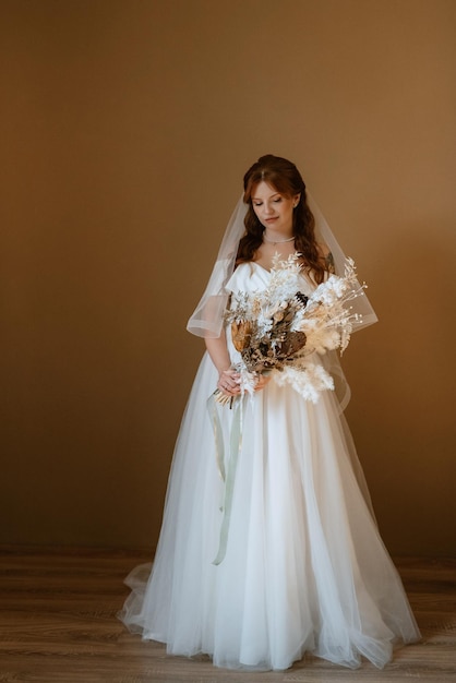 Portrait of a bride girl with red hair in a white wedding dress