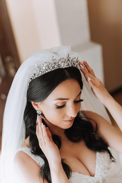 Portrait of the bride in the hotel room A beautiful young girl is dressed in a white wedding dress Modern wedding hairstyle Natural makeup