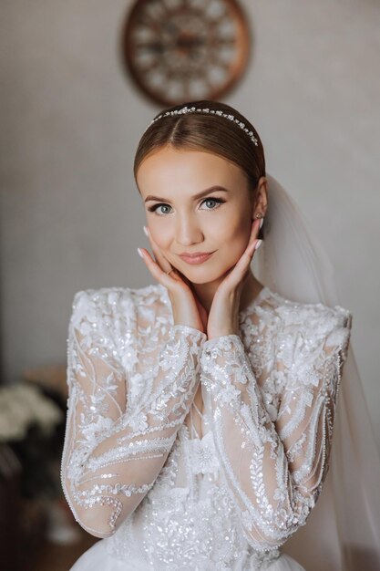 Portrait of the bride in the hotel room A beautiful young girl is dressed in a white wedding dress Modern wedding hairstyle Natural makeup