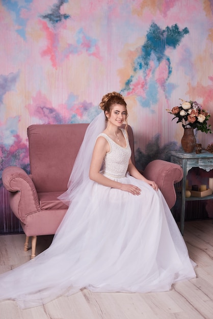 Portrait of bride in veil and jewelry at home on beautiful bridal boudoir.