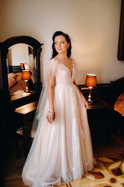 Portrait of the Bride in a wedding dress in the interior of the house near the mirror