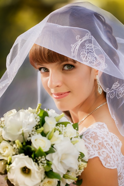 Portrait of bride with wedding bouquet in the park