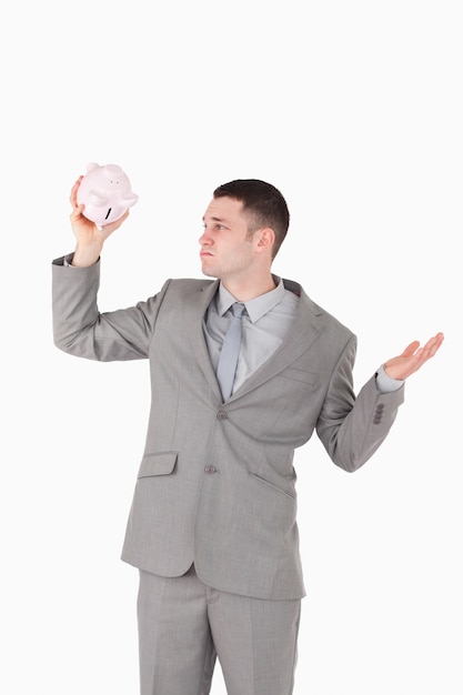 Portrait of a broke businessman looking at an empty piggy bank