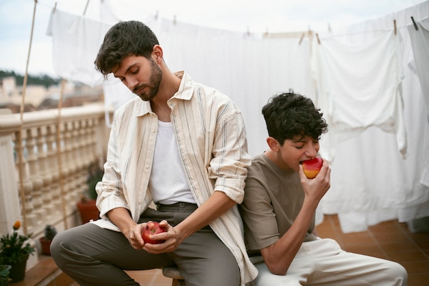 Photo portrait of brothers eating apples together outdoors