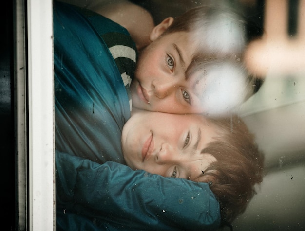 Photo portrait of brothers embracing seen through window