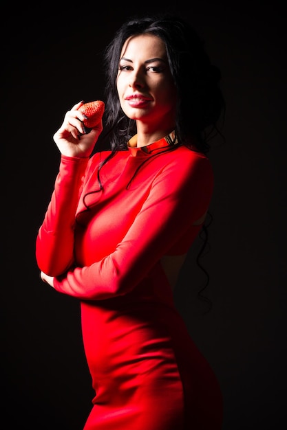 Portrait of a brunette beauty with honey dripping strawberry