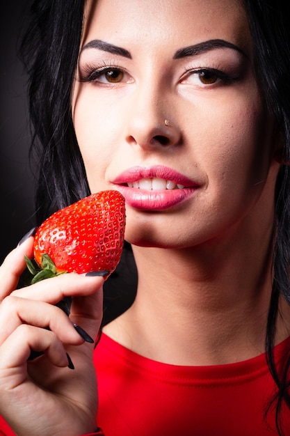 Portrait of a brunette beauty with honey dripping strawberry