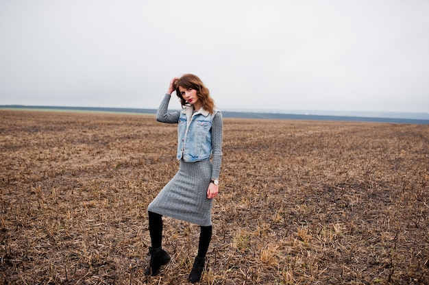 Photo portrait of brunette curly girl in jeans jacket at field.