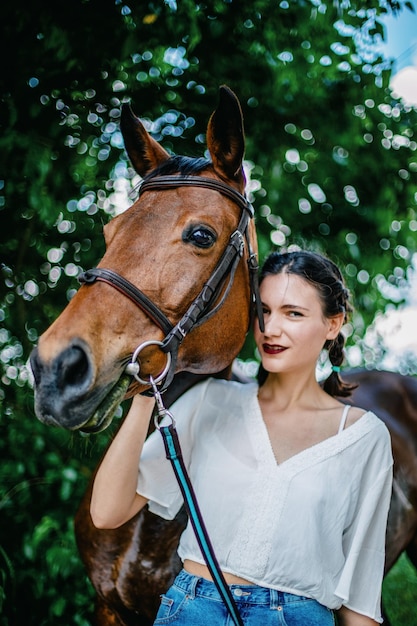 Portrait of a brunette girl next to her brown horse