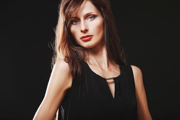 Portrait of a brunette girl with makeup on dark surface