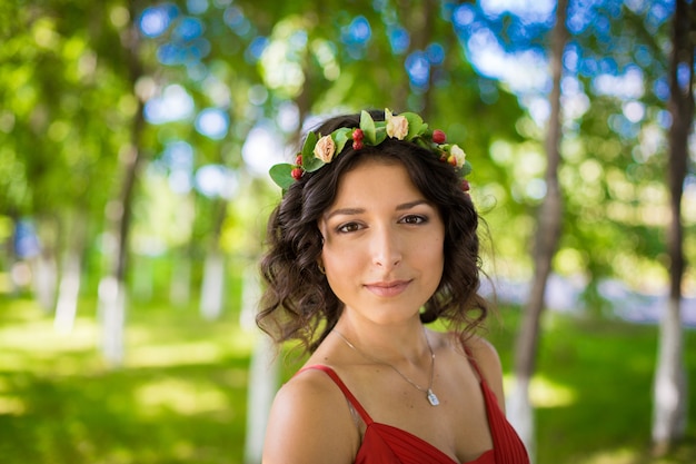 Ritratto di una bruna con fiori tra i capelli in un parco verde.