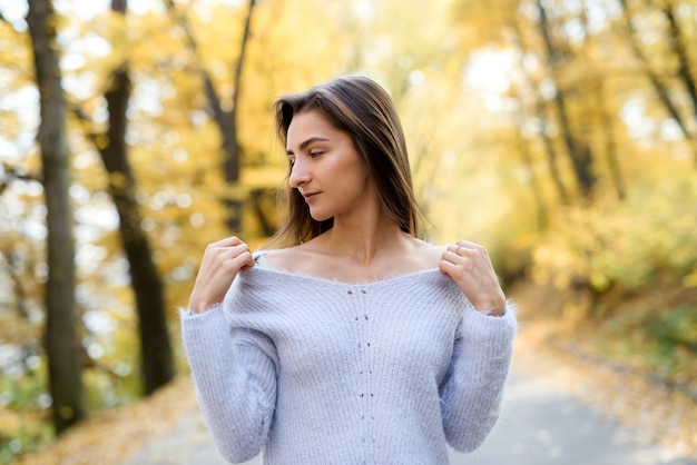 Portrait of brunette woman in casual wear in autumn park. Yellow colours around beautiful woman