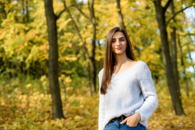 Portrait of brunette woman in casual wear in autumn park. Yellow colours around beautiful woman