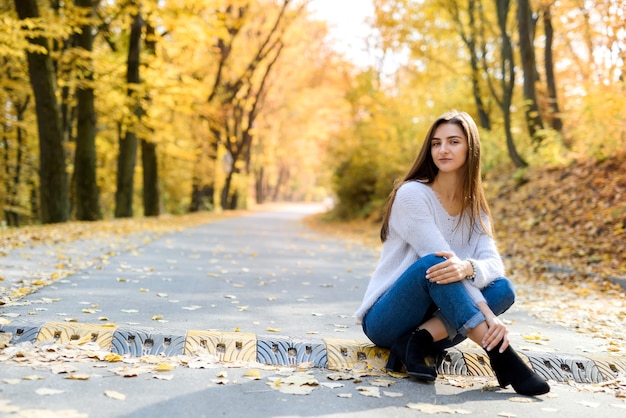 Ritratto di donna bruna in abbigliamento casual in autunno parco