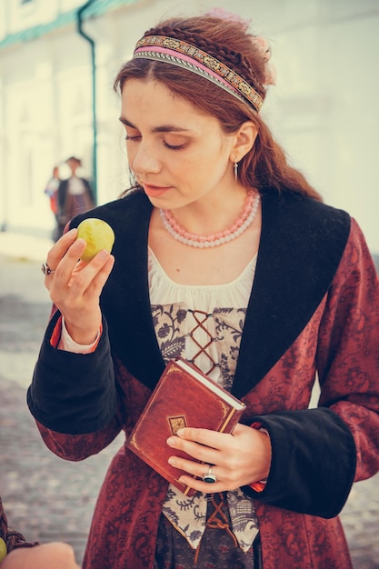 Portrait of brunette woman dressed in historical Baroque clothes with old fashion hairstyle outdoors